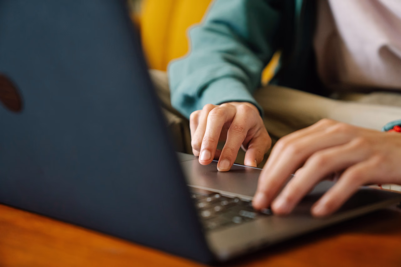 Close-up of a person's hands typing on a laptop keyboard