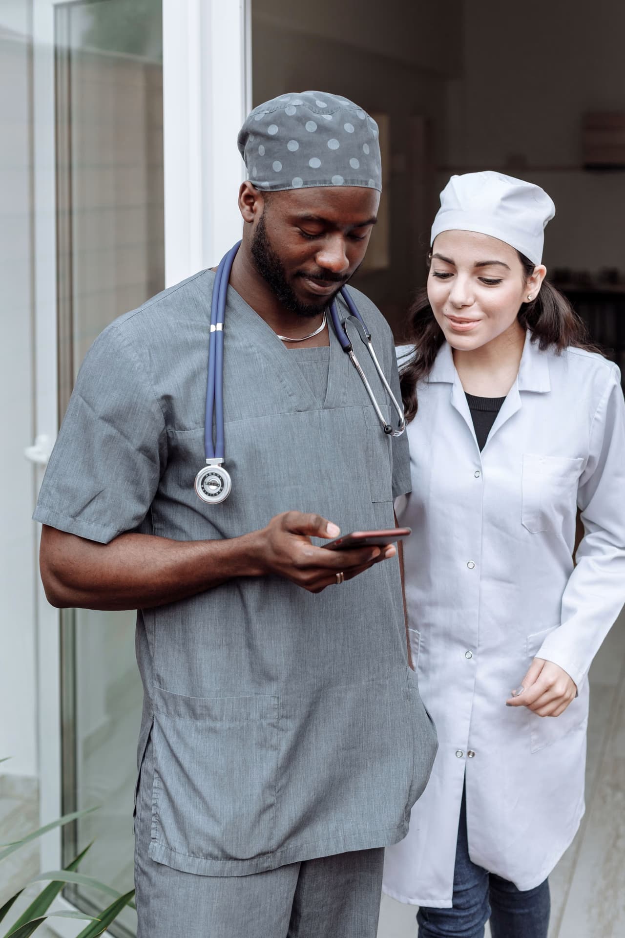 Two medical staff in a hospital corridor looking together at a mobile phone
